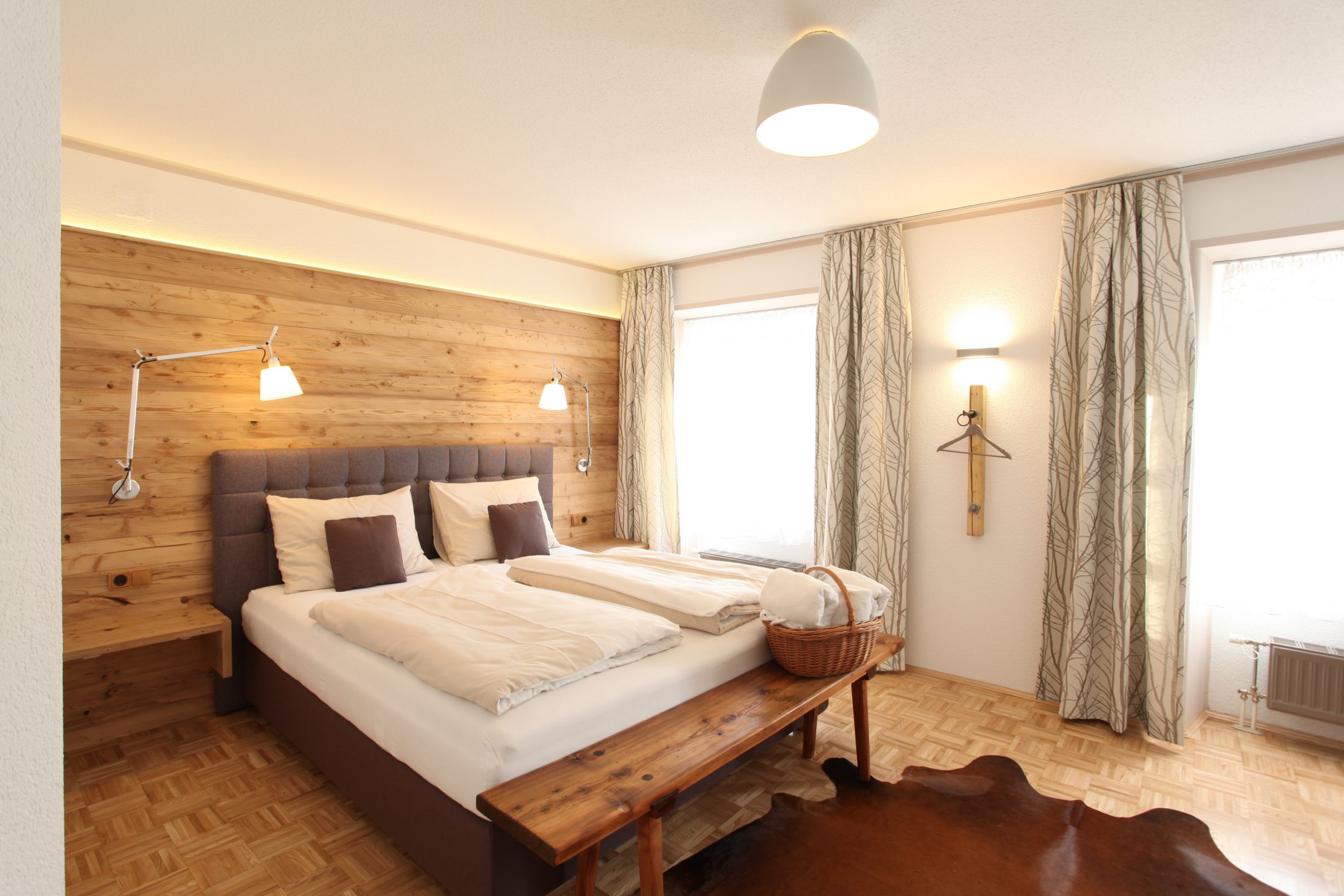 Hotelzimmer mit Fichtenholzvertäfelung und Boxspringbett