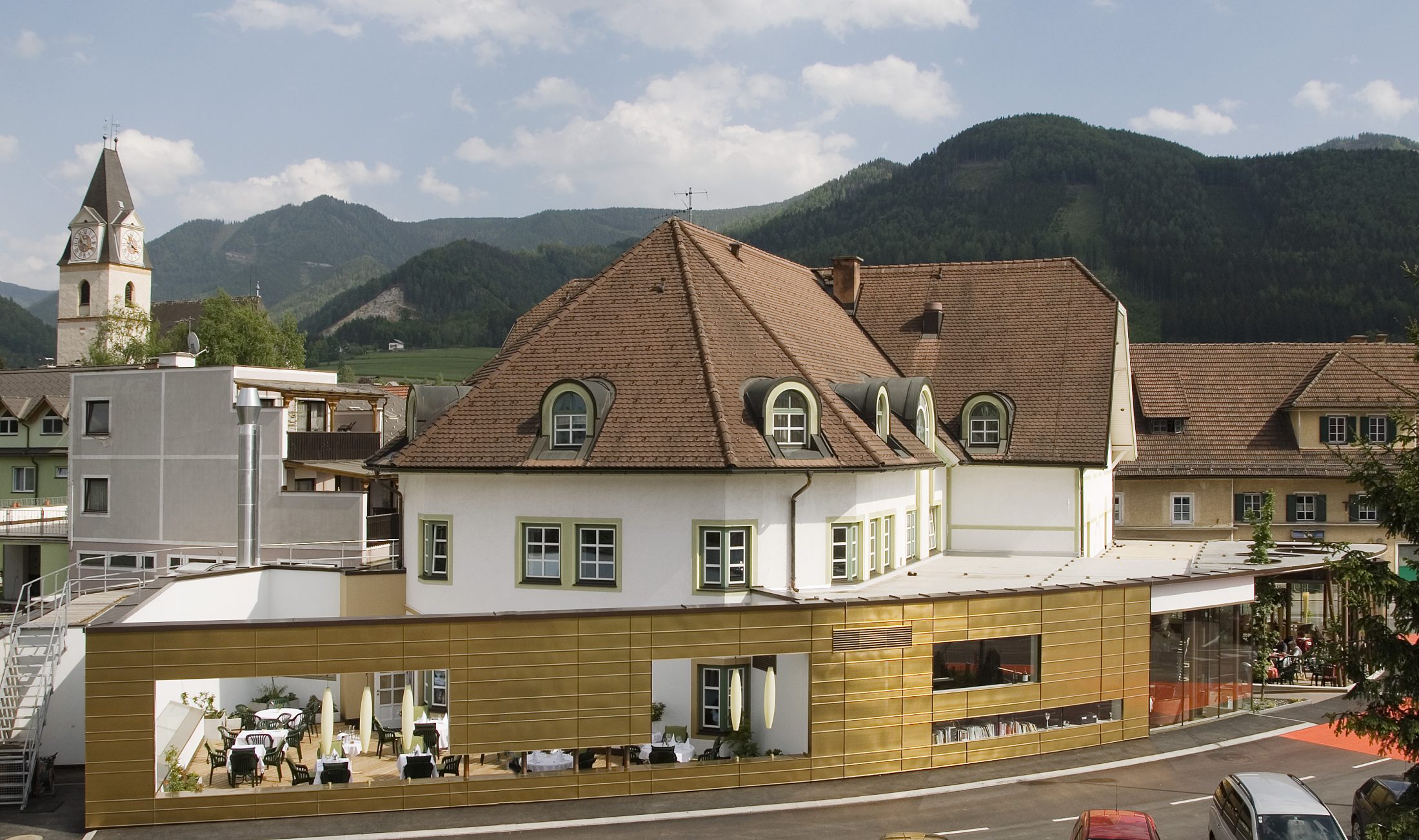 Hotel mit Kirche und Wald im Hintergrund