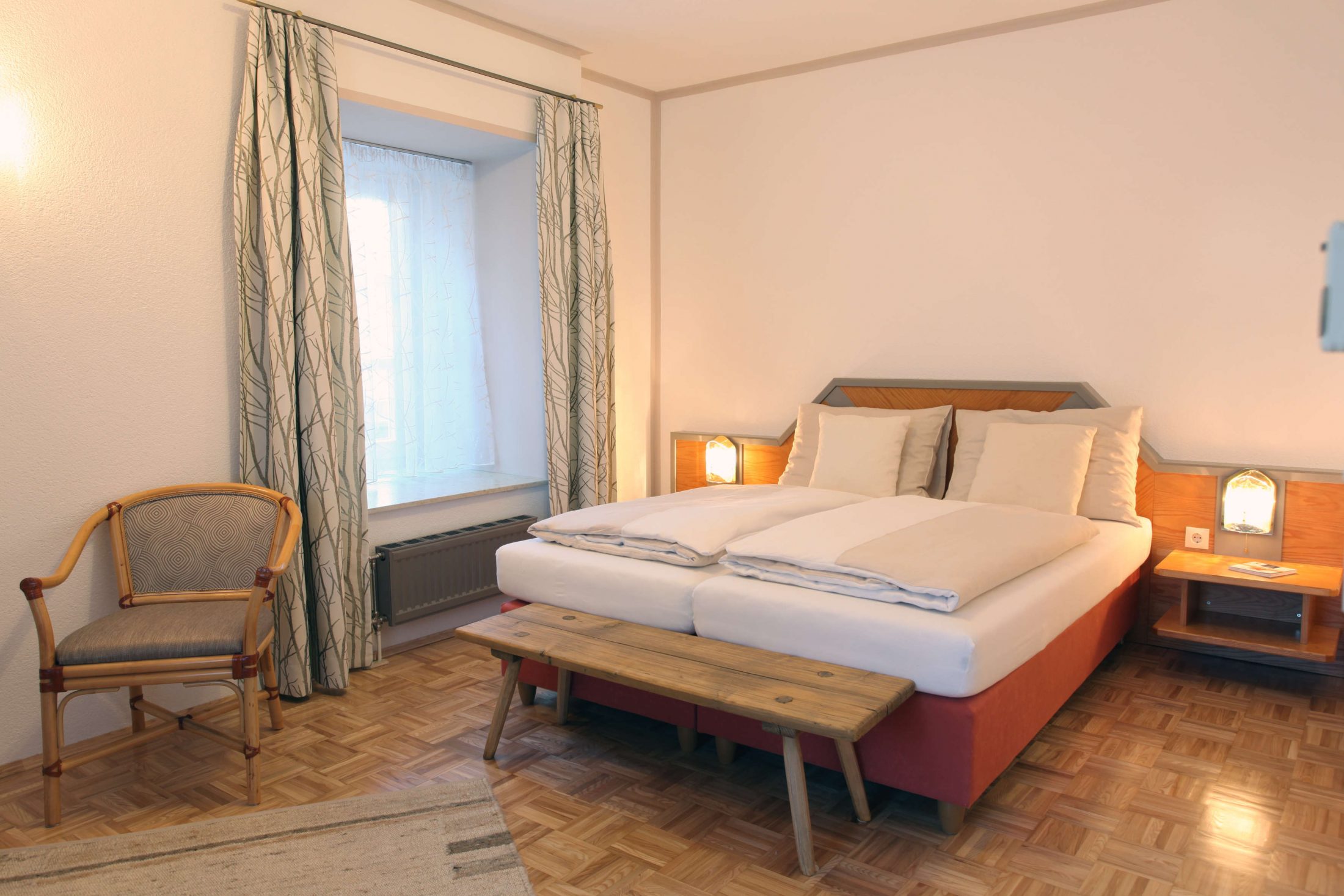 Hotelzimmer mit Doppelbett, rustikale Bank